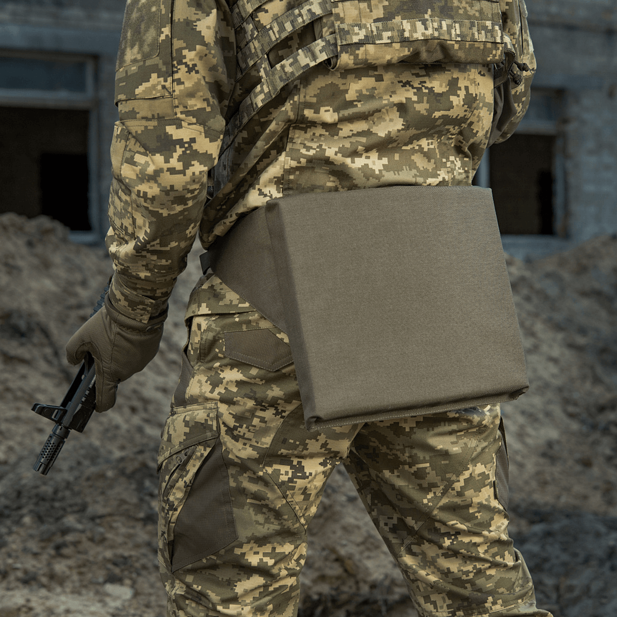 M-Tac Siddeunderlag med bælte i brug af soldat i camouflageuniform, set bagfra på en jordet undergrund.