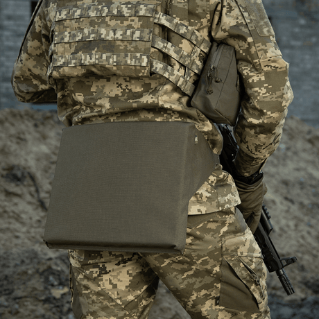 M-Tac sitteunderlag med belte på en kamuflasjeuniform, velegnet for utendørs bruk og militært utstyr.