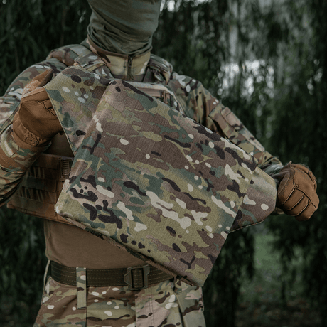 M-Tac sitteunderlag med belte – Multicam kamuflasje, beregnet for militært og friluftsbruk, holdt av person i feltklær.
