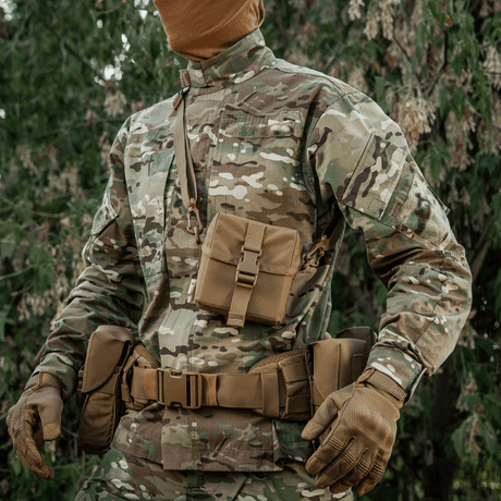 Militærperson i kamuflasjeuniform med M-Tac veske for nattkikkert PVS-14, klar til oppbevaring av nattkikkerter i naturmiljø.