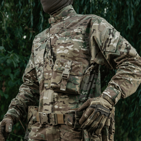 Person iført kamuflasjeuniform med M-Tac veske for nattkikkert PVS-14 hengende fra skulderen, utendørs bakgrunn.