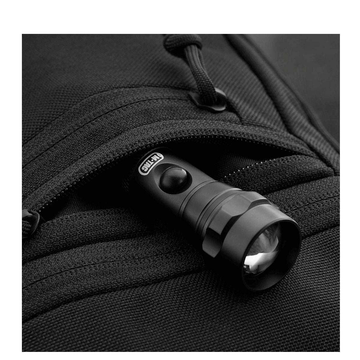 Lommelygte i en lynlåslomme på M-Tac Carry Sling Taske Elite Gen.IV skuldertaske til skjult bæring af våben, sort design.