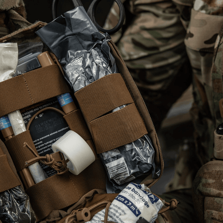 Taktisk M-Tac Medical Pouch Elite Rip Off førstehjælpstaske med elastiske stropper og indhold, åben til hurtig adgang i nødsituationer.