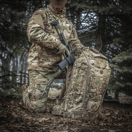M-Tac Ryggsekk Large Gen.III Elite i camouflagedesign sammen med taktisk utstyr i skogmiljø.