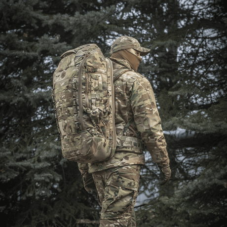 M-Tac Ryggsekk Large Gen.III Elite i taktisk bruk, båret av en person i camouflagedrakt ute i skogen.