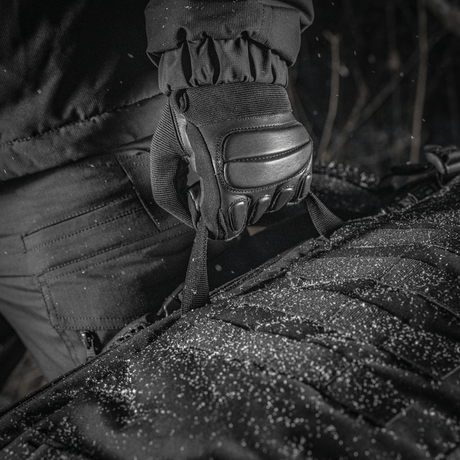 Nærbilde av M-Tac Ryggsekk Gen.II Elite Large i Cordura-materiale, holdt av hanskekledd hånd i snøvær.