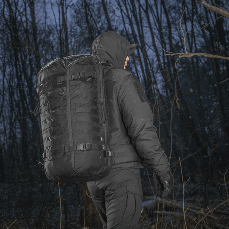 Person med M-Tac Ryggsekk Gen.II Elite Large i skog, iført vinterjakke, viser holdbarhet og funksjonalitet i kaldt vær.