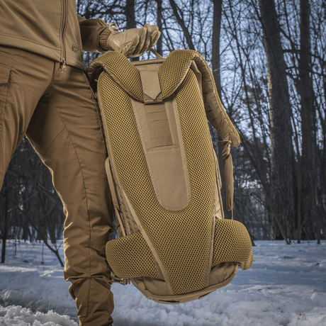 Person holder M-Tac Ryggsekk Gen.II Elite Large i snødekt skog, viser ergonomisk design og slitesterke materialer.