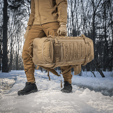 Person bærer M-Tac Ryggsekk Gen.II Elite Large i snødekt skog, laget av slitesterk Cordura med stilrent design.