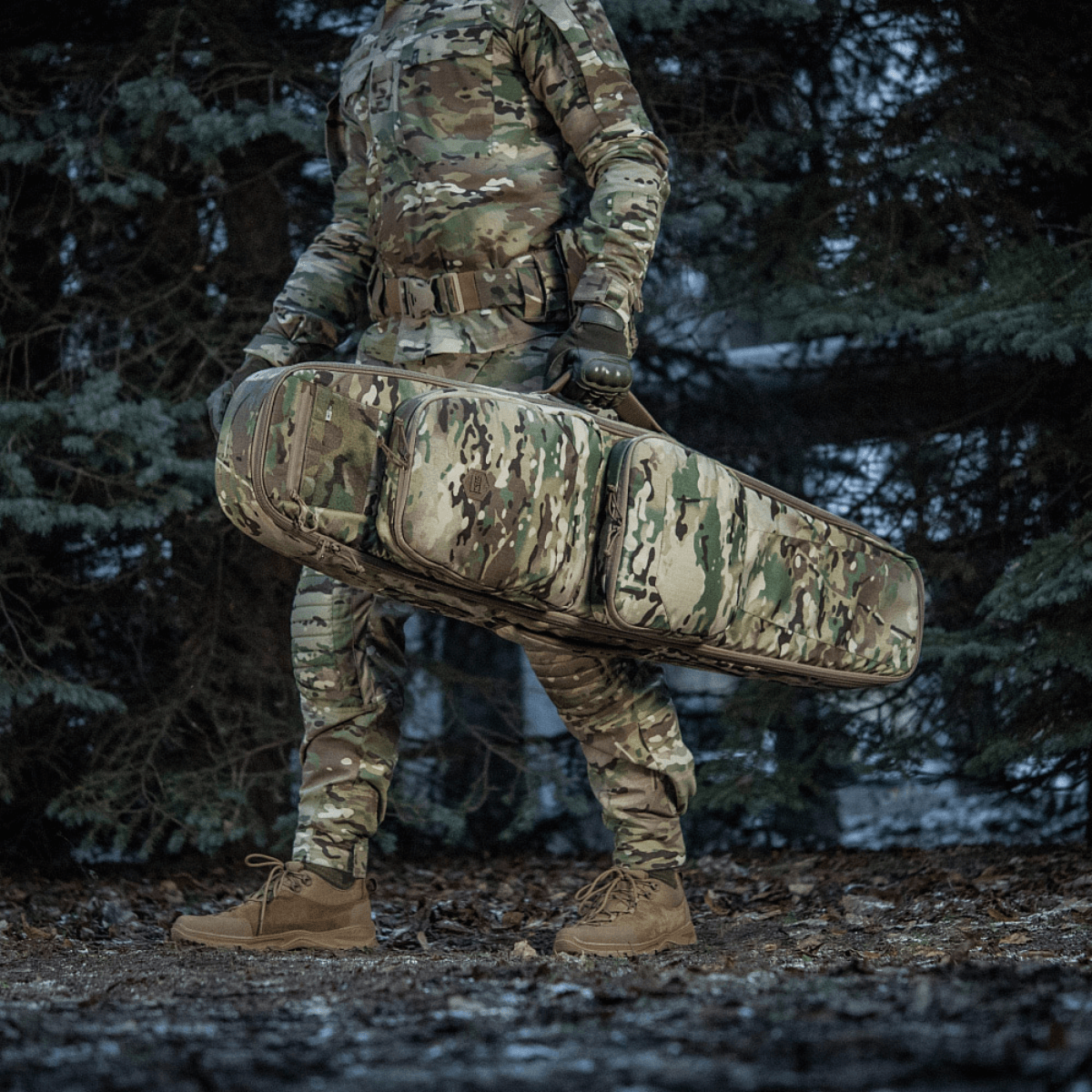 Soldat bærer M-Tac Gun Backpack Case 125 cm Gen.II Elite i en skov, iført camouflageuniform.