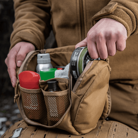 Person holder M-Tac toalettmappe Elite Gen.II fylt med hygieneartikler og småting.