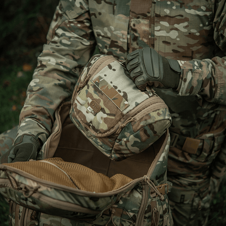 Person med M-Tac toalettmappe Elite Gen.II i kamuflasjedesign utendørs.