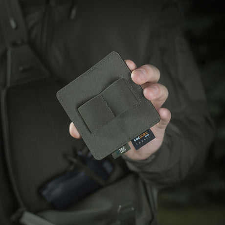 Person holder M-Tac Double Mag Pouch Hook Backed Magazine foran en mørk bakgrunn