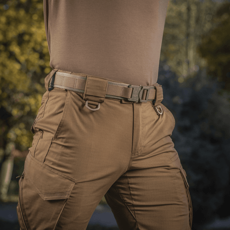 M-Tac Cobra Buckle Taktisk Bælte Laser Cut fastgjort på bukser i udendørs setting, ideelt til militær og politi.
