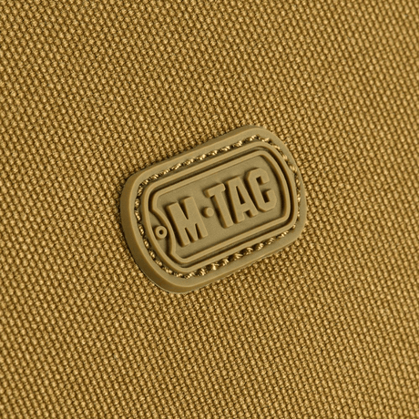 Nærbilde av M-Tac-logo på slitesterk 600D polyester med PVC-belegg, perfekt for kompakt oppbevaring og reisebruk.