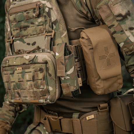 M-Tac Tourniquet Pouch Elastisk VELCRO Gen.II montert på taktisk vest i skogcamouflage, laget av robust Cordura 500D, rask tilgang.