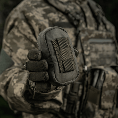 M-Tac PC Utility Pouch Elite i kamuflasje, Cordura-materiale med MOLLE-interface, vist i militært miljø. Taktisk veske for oppbevaring.
