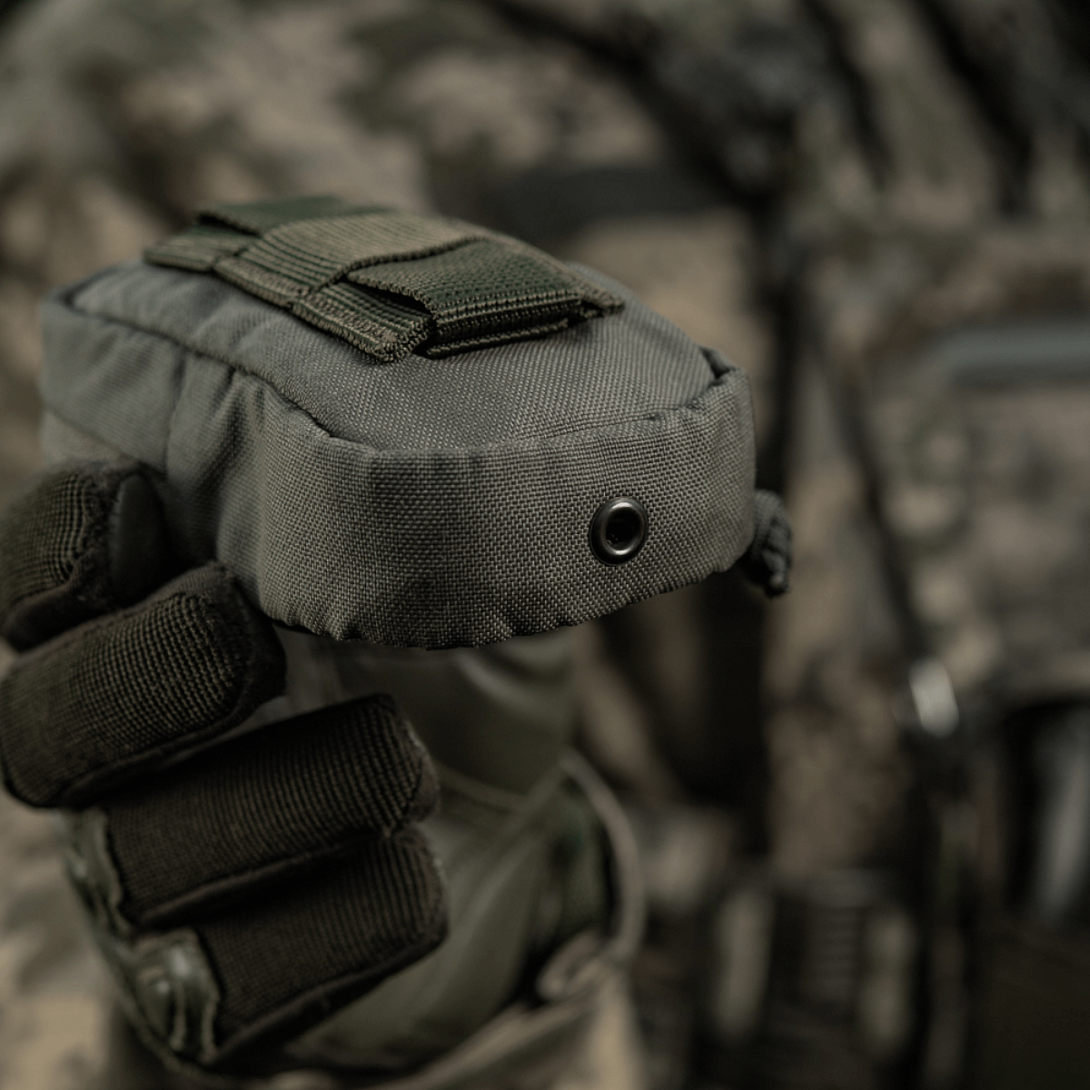 M-Tac PC Utility Pouch Elite i Cordura med MOLLE-interface, holdt af person i taktisk udstyr, ideel til små opbevaringsopgaver.