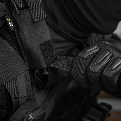 Person iført svart verneutstyr bruker M-Tac Tourniquet Pouch Elastisk med MOLLE Gen.II festet til vesten.