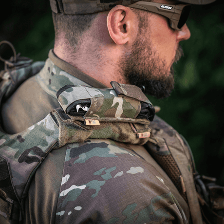 M-Tac Tourniquet Pouch Elastisk med MOLLE Gen.II på skulderen til en taktisk kledd mann utendørs, rask tilgang.
