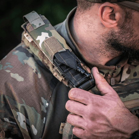 M-Tac Tourniquet Pouch Elastisk med MOLLE Gen.II festet på skulderen til en taktisk vest, viser rask tilgang og holdbarhet.