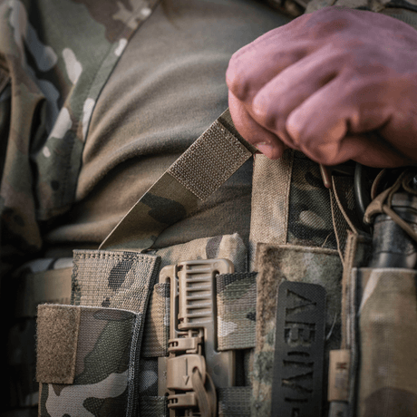 M-Tac Tourniquet Pouch Elastisk med MOLLE Gen.II i bruk, nærbilde på kamuflasjeutstyr. Ideell for rask tilgang til tourniquet.