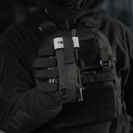 Taktisk operatør holder M-Tac Elastisk Tourniquet Pouch Molle Gen.III i Cordura Squadron med bred elastikk og lynrask tilgang.