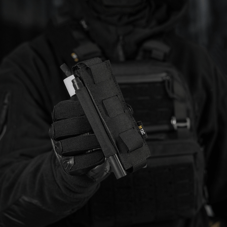 M-Tac Elastisk Tourniquet Pouch Molle Gen.III i bruk, holdt av en person iført taktisk utstyr, fremhever funksjonalitet og design.