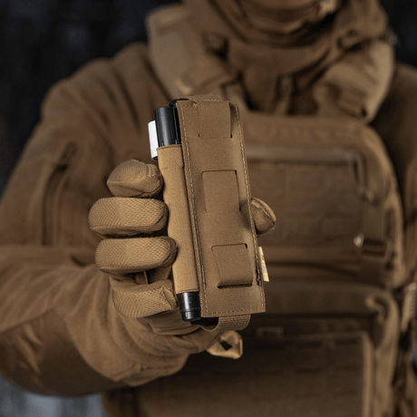 M-Tac Elastisk Tourniquet Pouch Molle Gen.III i bruk, holdt i taktisk hånd, rask tilgang til tourniquet, Cordura-materiale.