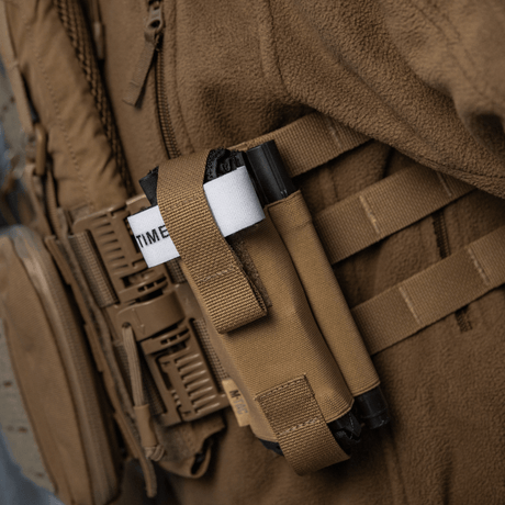 M-Tac Elastisk Tourniquet Pouch Molle Gen.III festet til utstyr, med elastikk og nylon for rask tilgang og oppbevaring av tourniquet.