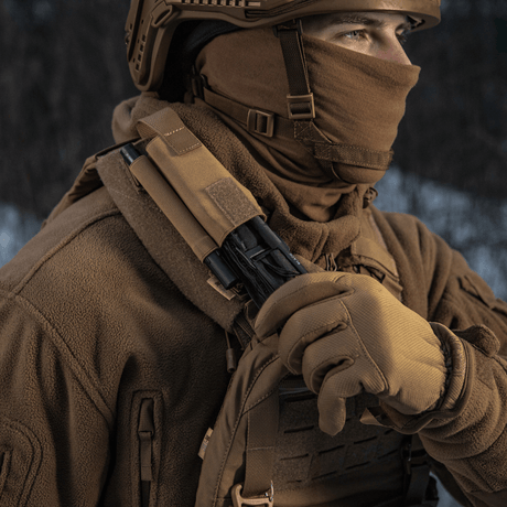 Person iført taktisk tøy med M-Tac Elastisk Tourniquet Pouch Molle Gen.III montert på skulderen i vinterlandskap.