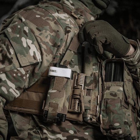 M-Tac Elastisk Tourniquet Pouch Molle Gen.III festet til taktisk vest med tourniquet og ekstrautstyr i militært område.