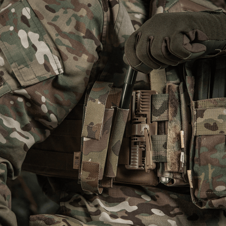 M-Tac Elastisk Tourniquet Pouch Molle Gen.III i bruk, montert på en militærvest i kamuflasjemønster med bred elastikk.