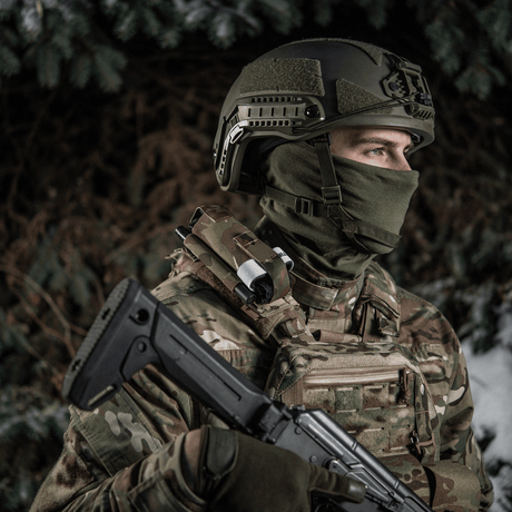 Soldat iført taktisk utstyr med rifle i vintermiljø.