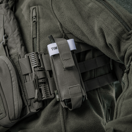 M-Tac Elastisk Tourniquet Pouch Molle Gen.III festet til utstyr, viser elastikk og hurtig tilgangsfunksjoner.