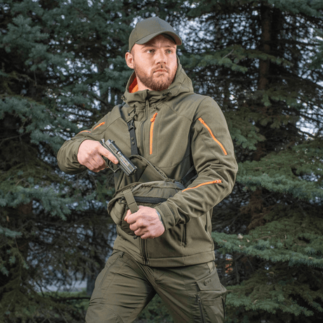 Mann bærer M-Tac Sphaera Hex Hardsling-veske Gen.II Elite i skogen, klar til rask handling med skjult bæring.