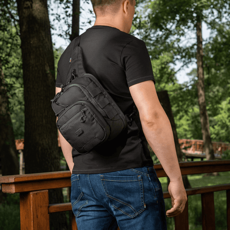 M‑Tac Cross Bag Elite Hex som slingveske for én skulder, holdt av en mann i sort t-skjorte, perfekt for daglig og taktisk bruk.