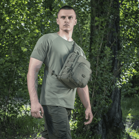 Mann bærer M-Tac Cross Bag Elite Hex i skogmiljø, ideell for daglig bruk og taktisk utstyr.