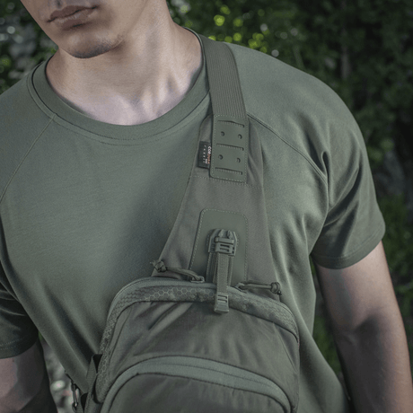 M-Tac Cross Bag Elite Hex i bruk på en person med grønn t-skjorte, perfekt for både hverdagsbruk og taktisk utstyr.