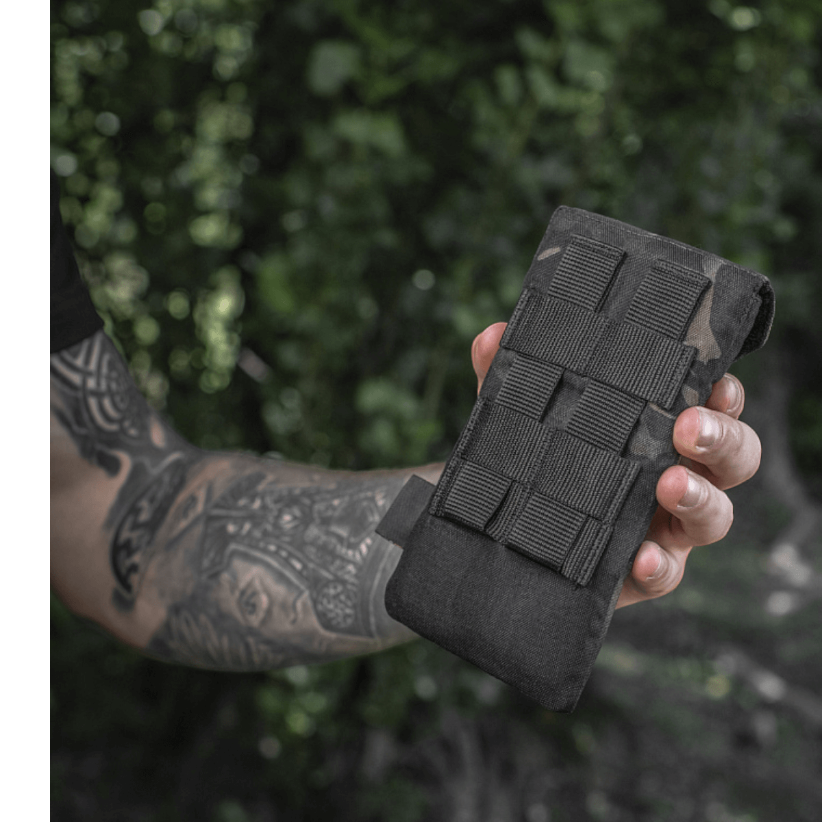 M-Tac Smartphone Lomme Elite Large Hex i sort CORDURA HEX på 1000D holdt i hånden med WJ magnetisk spænde lukket i en skov.