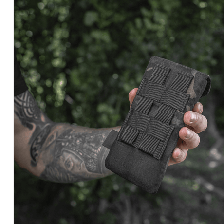 M-Tac Smartphonelomme Elite Large Hex i svart holdt av person i naturmiljø, laget av slitesterkt CORDURA HEX, for enheter opptil 6,5 tommer.