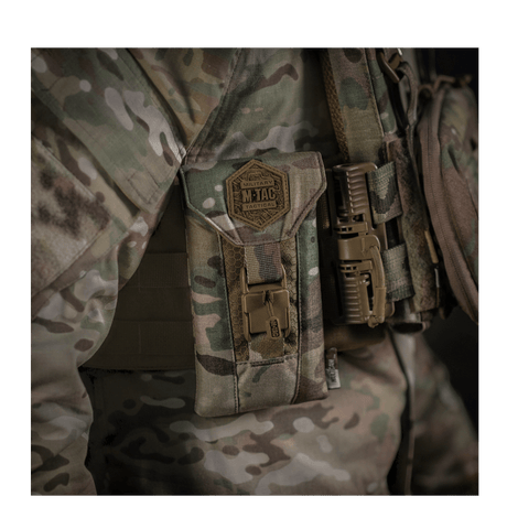 M-Tac Smartphonelomme Elite Large Hex i CORDURA HEX-materiale, vist montert på taktisk utstyr med kamuflasjebakgrunn.