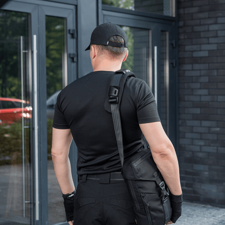 Mann med veske iført M‑Tac skulderrempute 50 mm Elite ved inngangsdør.