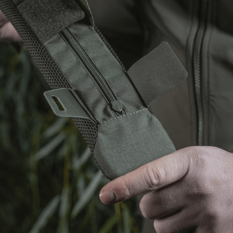 Person holder M‑Tac skulderrempute 50 mm Elite i robust Cordura-materiale med glidelås-lukking og 3D mesh-ventilasjon.