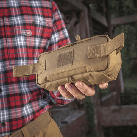 M-Tac Horizontal Medical Pouch Elite i hånden på en person, slitesterkt feltkit for førstehjelp med indre organizer og vanntett glidelås.