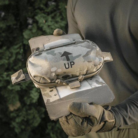 M‑Tac Horizontal Medical Pouch Elite holdt av en person i naturen, kamuflasjedesign og Cordura 500D-materiale.