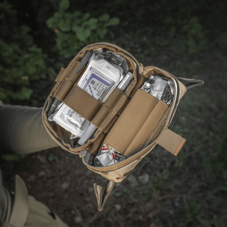 M‑Tac Horizontal Medical Pouch Elite i bruk, åpen veske viser innhold av feltkit for førstehjelp i Cordura 500D med YKK AquaGuard-glidelås.