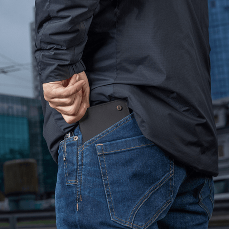 Person legger M‑Tac Pung Slim Elite i baklommen på jeans.