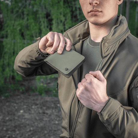 Mann holder M-Tac Pung Slim Elite Gen. II i capslomme, kompakt design av polymerkompositt med kortlommer og myntlomme.