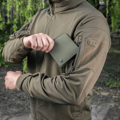 M-Tac Pung Slim Elite Gen. II i grønn polymerkompositt holdes av person i jakke, viser kompakt design og slitestyrke.